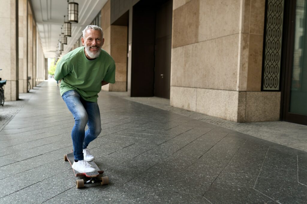 Active happy cool older man skater riding skateboard in the city street.